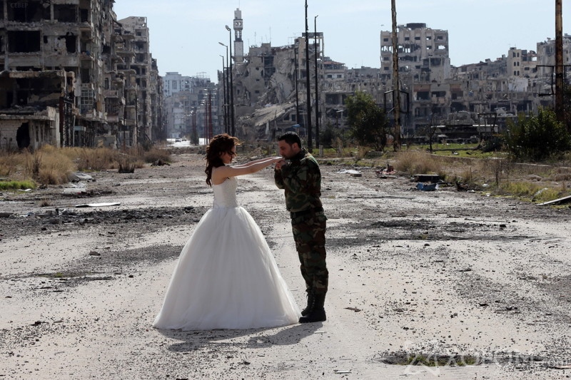 Newly-wed Syrian couple Nada Merhi,18, and Syrian army soldier Hassan Youssef,27, pose for a wedding picture amid heavily damaged buildings in the war ravaged city of Homs on February 5, 2016. A Syrian photographer thought of using the destruction of Homs to take pictures of newly wed couples to show that life is stronger than death. / AFP / JOSEPH EID (Photo credit should read JOSEPH EID/AFP/Getty Images)