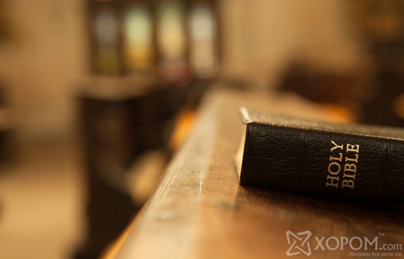 Holy Bible on a wooden church bench.