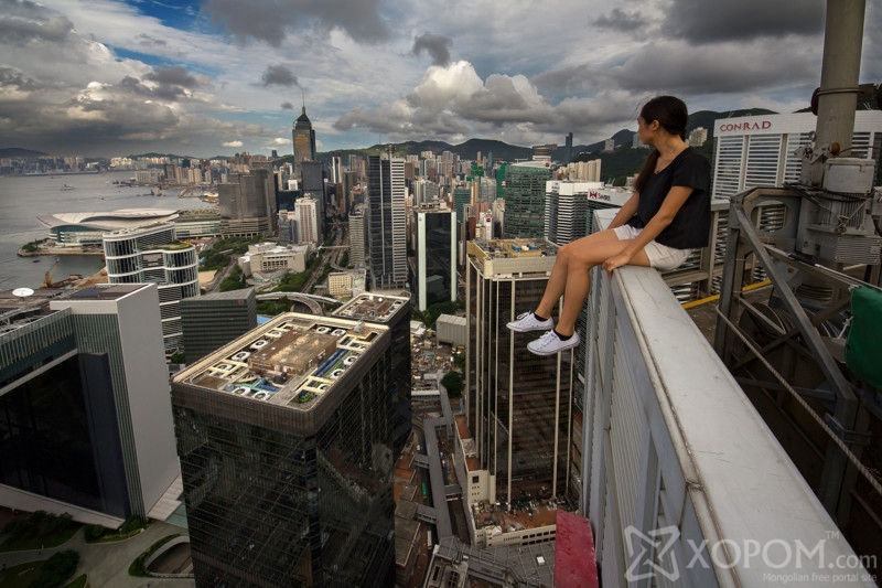PIC BY ALEXANDER REMNOV / CATERS NEWS - (PICTURED One of the crazy climbers sits on the edge of a skyscraper in Hong Kong) These breath-taking images taken from the top of skyscrapers are wrong on so many levels. Captured using a specially adapted selfie stick, the sweat inducing images show the lengths some people will go to for the most extreme self portrait. Pictured at heights over 360 metres in the air, the nerve shredding photographs show the group of photographers dangling by one hand and even tip-toeing across tiny ledges. Seemingly unfazed by the dazzling heights, the barmy bunch ventured around the city of Hong Kong in search of any building that caught their eye. SEE CATERS COPY **NOT FOR SALE / USE IN RUSSIA / POLAND**